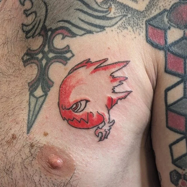 Tatouage Bombo en rouge et noir sur le torse, réalisé par Hysil Tattoo à La Flèche